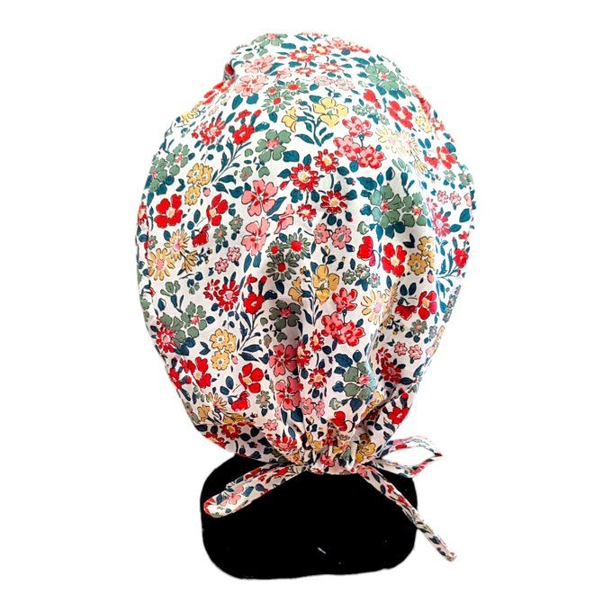 son tissu blanc est sublimé par des motifs floraux aux teintes de rouge, vert et jaune, apportant un