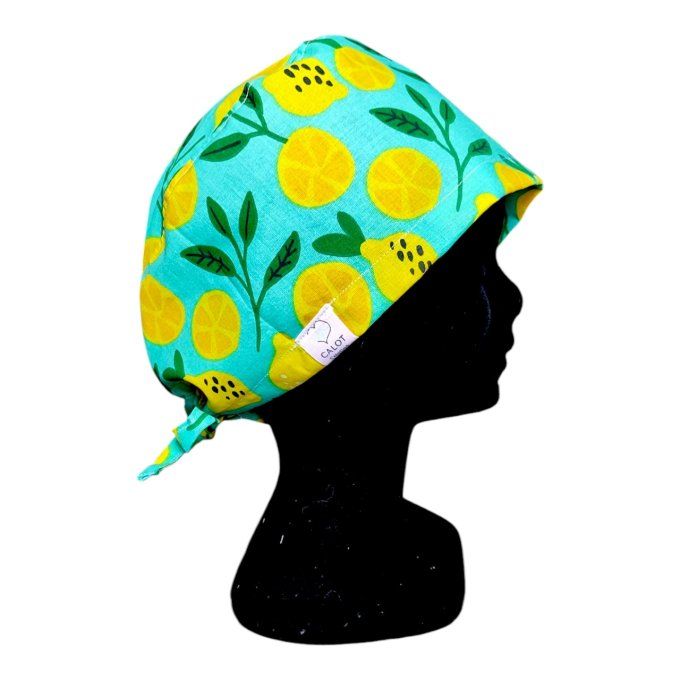 un fond turquoise vif parsemé de citrons jaunes entiers et tranchés, accompagnés de branches feuillu
