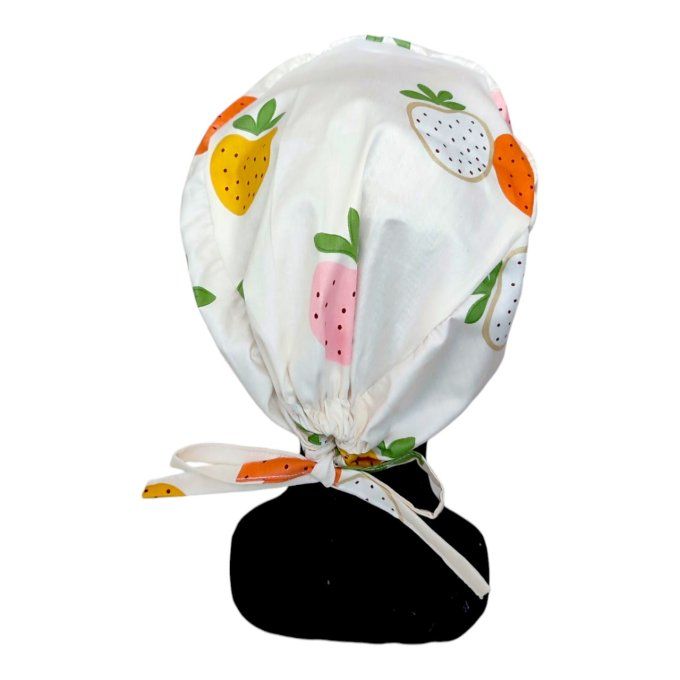 avec ses fraises blanches et roses aux contours dorés sur un fond clair, ce calot apporte une touche