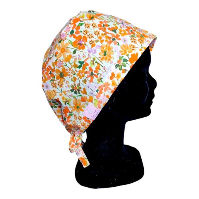 son tissu blanc cassé est sublimé par un motif éclatant de fleurs dans des tons orangés, verts et to