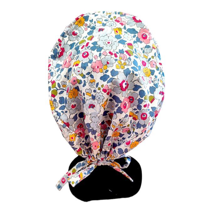 son tissu blanc est sublimé par des motifs floraux dans des nuances de bleu, rose et jaune, apportan