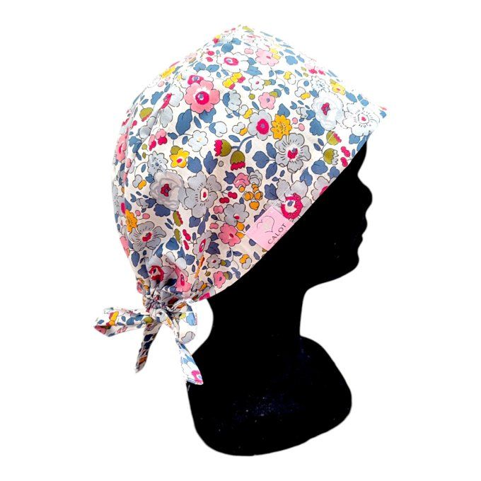 son tissu blanc est sublimé par des motifs floraux dans des nuances de bleu, rose et jaune, apportan
