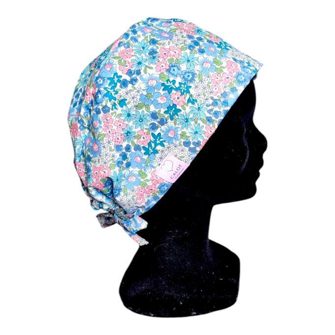 son tissu bleu clair est orné de délicats motifs floraux dans des tons pastel de rose, bleu et vert,